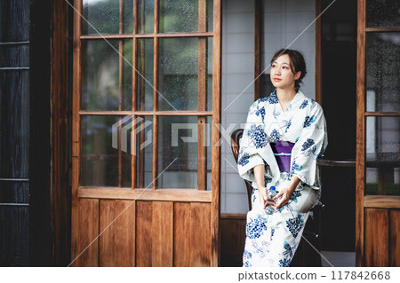 A young woman in a yukata sitting on the veranda 117842668
