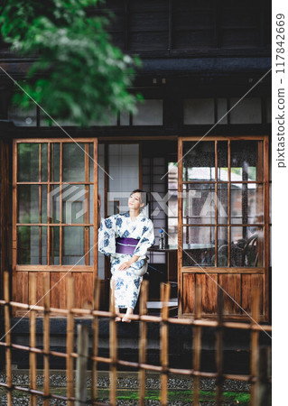 一位穿著浴衣的年輕女子坐在門廊上 一位穿著浴衣的年輕女子坐在門廊上 117842669