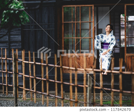 一位穿著浴衣的年輕女子坐在門廊上 一位穿著浴衣的年輕女子坐在門廊上 117842670