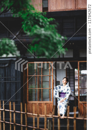 A young woman in a yukata sitting on the veranda 117842672