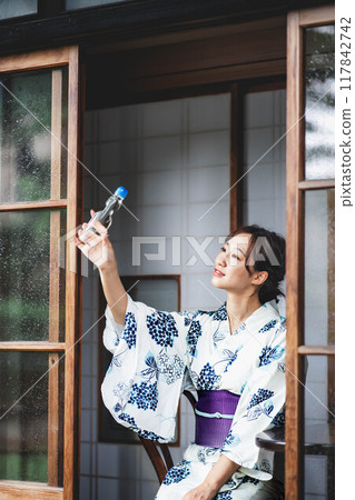 A woman in a yukata with a ramune A woman in a yukata with a ramune 117842742