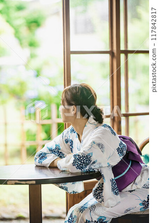 一位穿著浴衣的年輕女子坐在古老民宅的窗邊 117842817