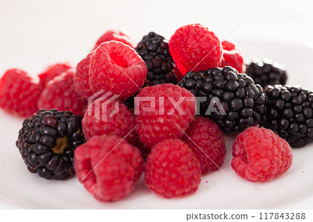 Handful of raspberry and blackberry berries on white background Handful of raspberry and blackberry berries on white background 117843288