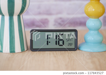 A digital clock showcasing the time at midday, beautifully placed on decorative stands 117843527