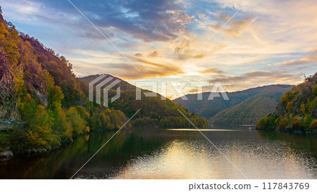 lake in mountains on a sunny evening. forest reflecting in the water. beautiful scenery of romania in autumn season. picturesque cloudscape lake in mountains on a sunny evening. forest reflecting in the water. beautiful scenery of romania in autumn season. picturesque cloudscape 117843769