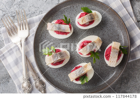 Festive deviled eggs stuffed with beets and herring close-up in a plate. Horizontal top view 117844178