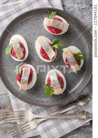 Hard-boiled eggs stuffed with beetroot salad and herring close-up in a plate. Vertical top view Hard-boiled eggs stuffed with beetroot salad and herring close-up in a plate. Vertical top view 117844181