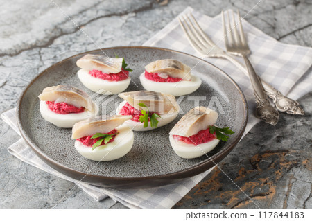 Festive deviled eggs stuffed with beets and herring close-up in a plate. Horizontal Festive deviled eggs stuffed with beets and herring close-up in a plate. Horizontal 117844183