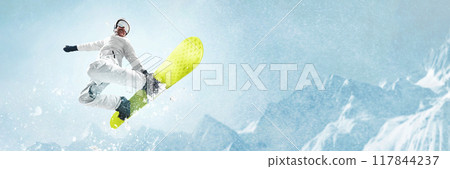 Snowboarder performing high-flying trick in air, against stunning backdrop of snow-covered mountains, capturing thrill and freedom of winter sports. 117844237