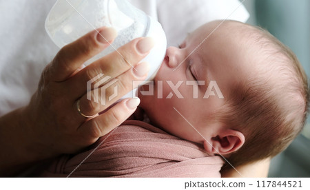 Mother Feeds Newborn Baby Formula From A Bottle As The Infant Consumes It 117844521