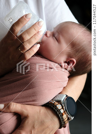 Mother Feeds Newborn Baby Formula From A Bottle While The Infant Drinks The Milk 117844527