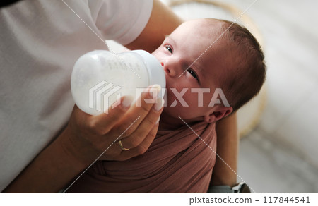 Mother Feeds Newborn Baby Formula From A Bottle As The Infant Consumes It 117844541