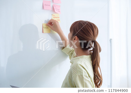 A young woman visualizing issues in the office 117844900