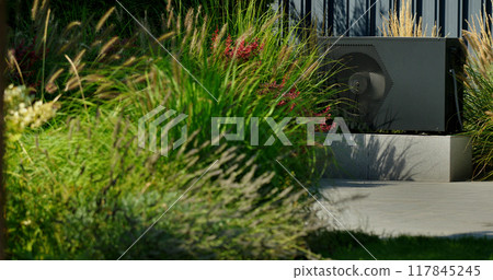 Modern heat pump unit installed by a backyard pool, surrounded by vibrant greenery and blooming plants. 117845245