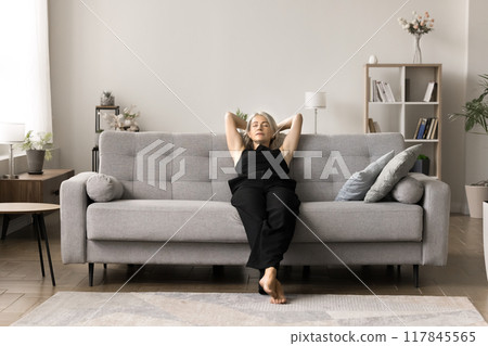 Peaceful attractive middle-aged woman leaned on comfortable couch Peaceful attractive middle-aged woman leaned on comfortable couch 117845565