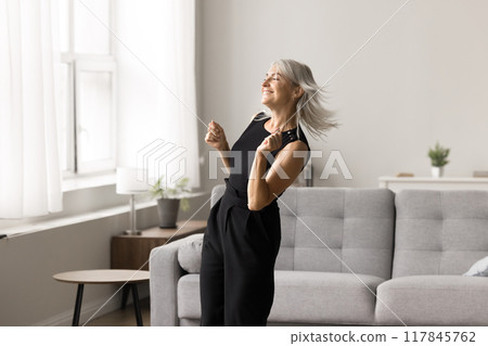 Carefree mature woman dancing, enjoy weekend in fashionable living room Carefree mature woman dancing, enjoy weekend in fashionable living room 117845762