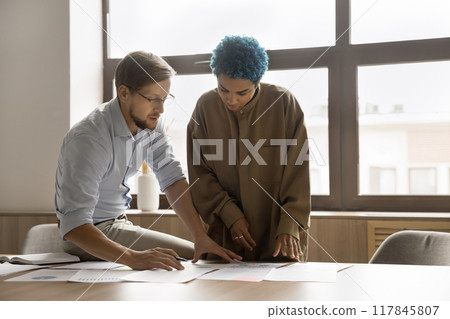 Two multiethnic colleagues working together in office Two multiethnic colleagues working together in office 117845807