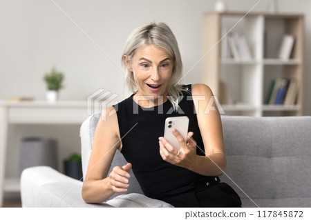 Mature woman feels happy reading great news on smartphone 117845872