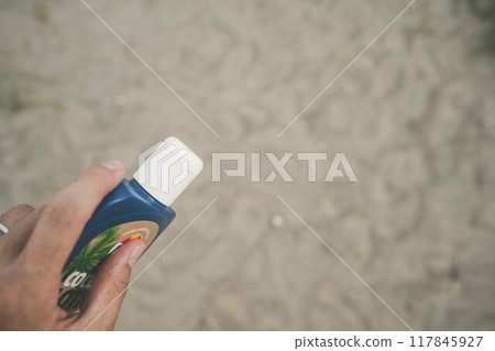 Holding sunscreen at the beach 117845927