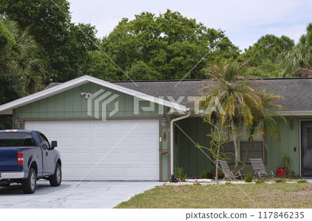 Vehicle parked in front of wide garage double door on paved driveway of typical contemporary american home Vehicle parked in front of wide garage double door on paved driveway of typical contemporary american home 117846235