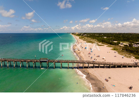 Venice fishing pier in Florida on sunny summer day. Bright seascape with surf waves crashing on sandy beach Venice fishing pier in Florida on sunny summer day. Bright seascape with surf waves crashing on sandy beach 117846236