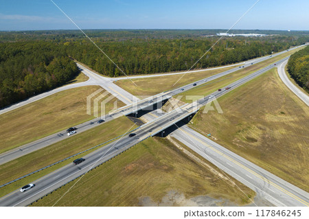 View from above of busy american highway with fast moving traffic between woods. Interstate transportation concept View from above of busy american highway with fast moving traffic between woods. Interstate transportation concept 117846245