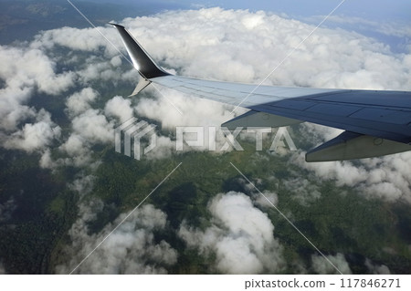 View through airplane window of commercial jet plane wing flying high in the sky. Air travelling concept View through airplane window of commercial jet plane wing flying high in the sky. Air travelling concept 117846271