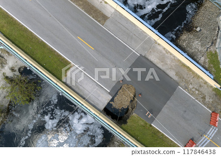 Roadworks site. Reconstruction of damaged road bridge destroyed by river after flood water washed away asphalt. Rebuilding of ruined transportation infrastructure 117846438