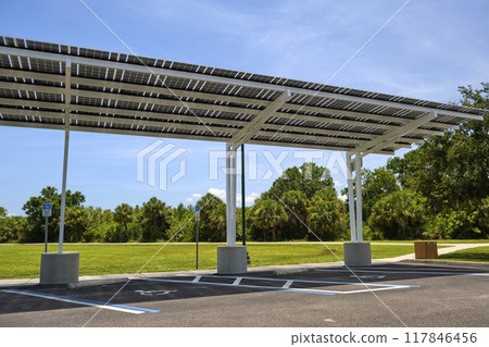Solar panels installed as shade roof over parking lot for parked electric cars for effective generation of clean electricity. Photovoltaic technology integrated in urban infrastructure Solar panels installed as shade roof over parking lot for parked electric cars for effective generation of clean electricity. Photovoltaic technology integrated in urban infrastructure 117846456