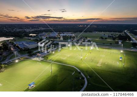 Sportsmen playing football game on illuminated stadium in public sports park 117846466