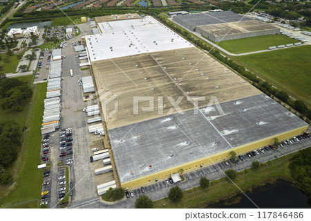 Top view of giant logistics center with many commercial trailer trucks unloading and uploading retail products for further shipment. Global economy concept 117846486