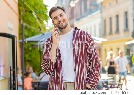 Portrait of happy man having remote conversation talking on smartphone, good news gossip in city Portrait of happy man having remote conversation talking on smartphone, good news gossip in city 117846534