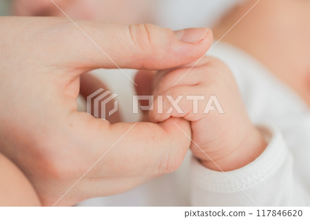 Happy family. Tiny newborn infant baby little hand on mother hand palm. Newborn baby holding parent finger after birth. Mom baby at home. Support protection of new life. Handle with care 117846620
