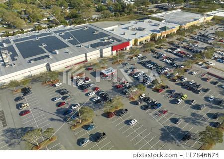 Many parked cars on store parking lot with lines and markings for parking places and directions. Place for vehicles in front of a shopping mall center 117846673
