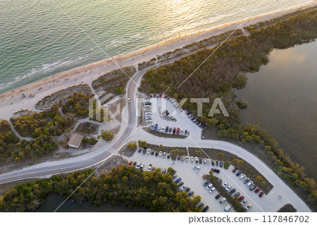 Parking lot for tourists cars in front of ocean beach with soft white sand in Florida. Popular vacation spot at sunset Parking lot for tourists cars in front of ocean beach with soft white sand in Florida. Popular vacation spot at sunset 117846702