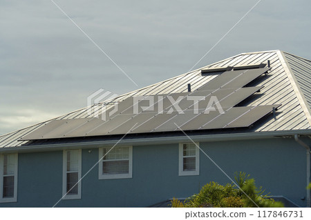 Residential house with rooftop covered with solar photovoltaic panels for producing of clean ecological electrical energy in suburban rural area. Concept of autonomous home 117846731