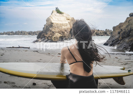 Back view of a woman surfing in the ocean Back view of a woman surfing in the ocean 117846811