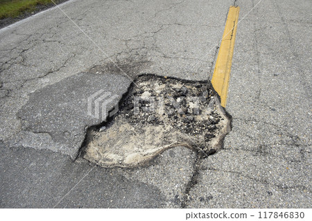 Damaged american road surface with deep pothole. Ruined street in urgent need of repair 117846830
