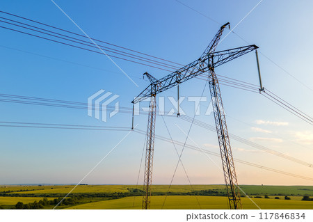 Dark silhouette of high voltage towers with electric power lines at sunrise. 117846834