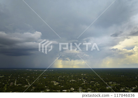 Dark stormy clouds forming on gloomy sky during heavy rainfall season over suburban town area Dark stormy clouds forming on gloomy sky during heavy rainfall season over suburban town area 117846836