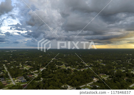 Dark stormy clouds forming on gloomy sky during heavy rainfall season over suburban town area in evening 117846837