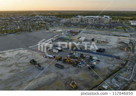 Development of real estate market in the USA. Aerial view of large construction site with building equipment on prepared soil in american rural area 117846850