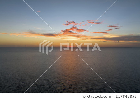 Dramatic bright red sky at ocean sunset, soft evening clouds over sea dark water 117846855