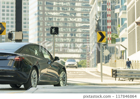 Electric car on American street at intersection with traffic lights in Miami, Florida. Electrical vehicle transportation. 117846864