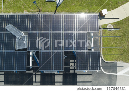 Failing of photovoltaic technology integrated in urban infrastructure. Hurricane wind damage to solar panels installed as shade roof over parking lot for parked electric cars 117846881