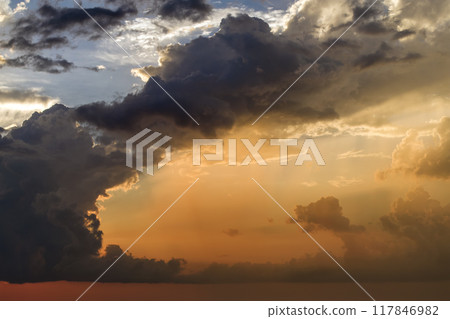 Bright sunset with setting sun behind vivid orange and yellow clouds 117846982