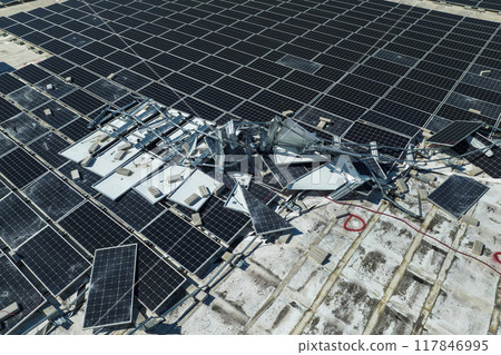 Broken down photovoltaic solar panels destroyed by hurricane Ian winds mounted on industrial building roof for producing green ecological electricity. Consequences of natural disaster 117846995