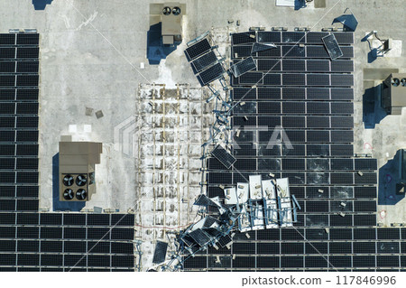 Broken down photovoltaic solar panels destroyed by hurricane Ian winds mounted on industrial building roof for producing green ecological electricity. Consequences of natural disaster 117846996