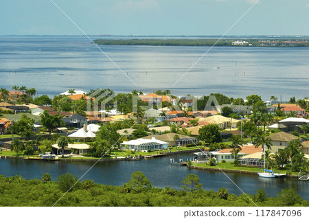Aerial view of residential suburbs with private homes located on gulf coast near wildlife wetlands with green vegetation on sea shore. Living close to nature concept 117847096