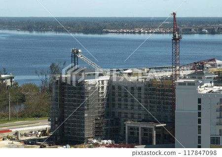 Aerial view of ruined by hurricane Ian construction crane on high apartment building site in Port Charlotte, USA Aerial view of ruined by hurricane Ian construction crane on high apartment building site in Port Charlotte, USA 117847098